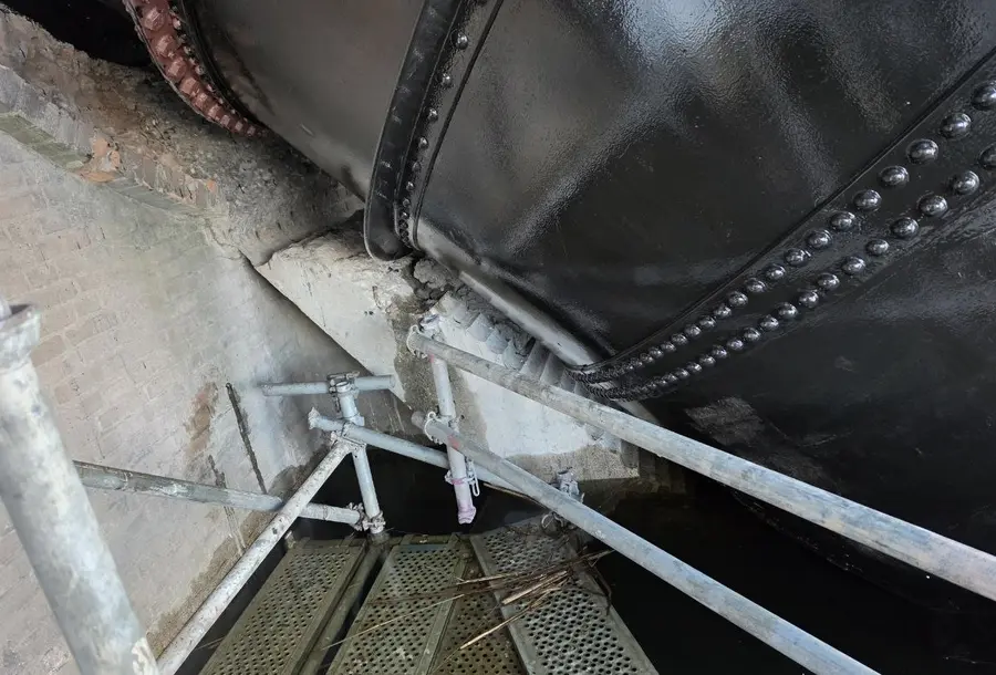 Steel bridge girder on a masonry abutment, accessed by scaffold