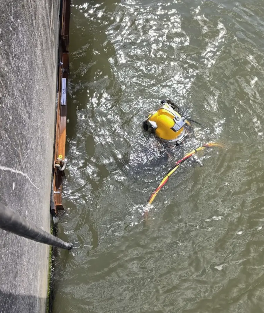 Commercial diver with umbilical alongside a quay wall
