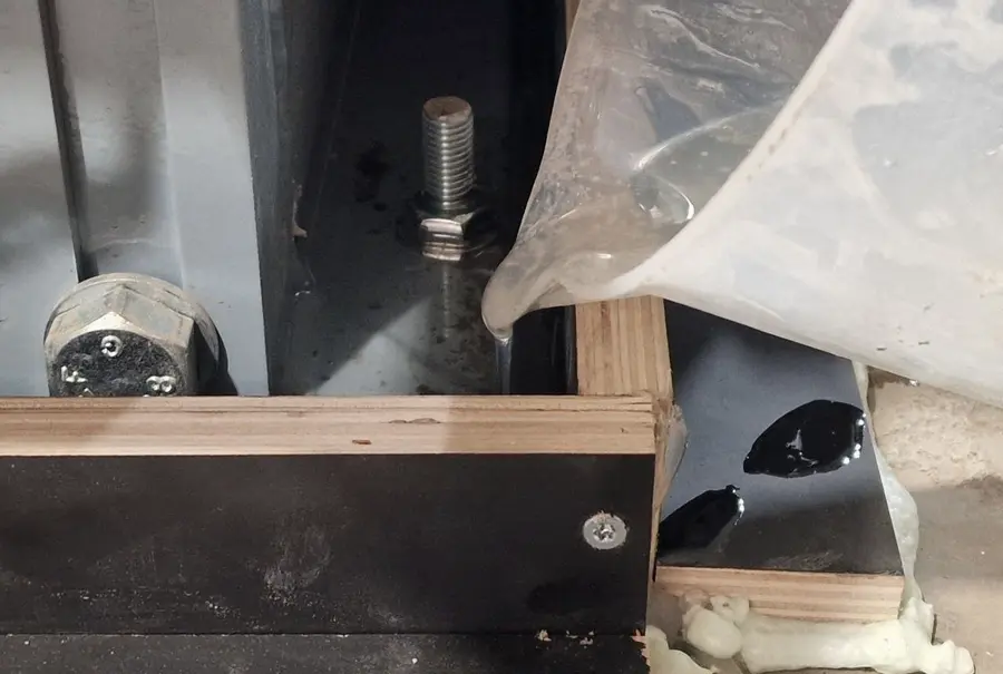 Grout being poured into formwork around a steel base plate