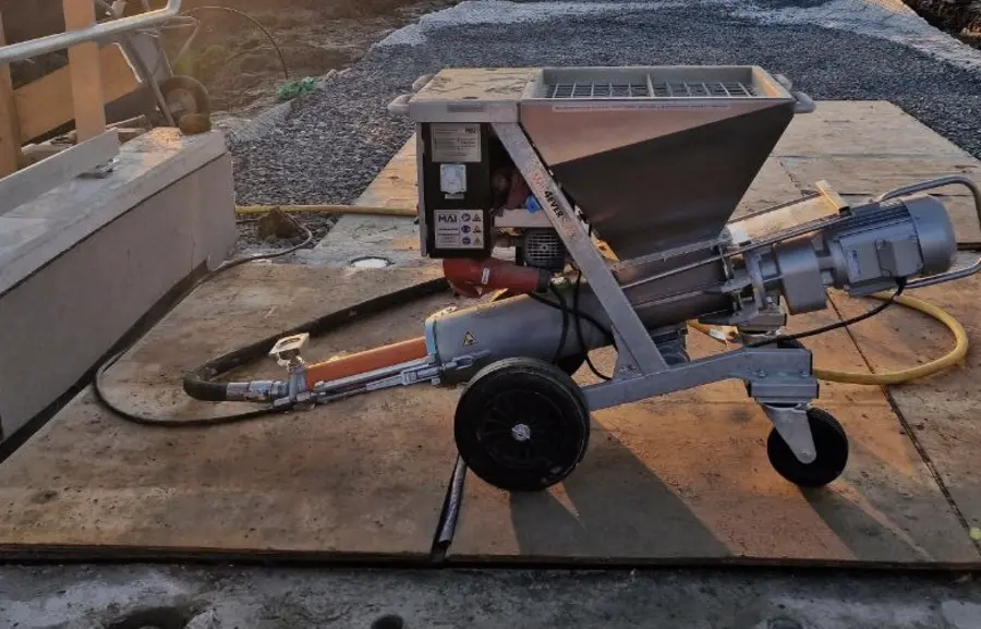 Grout pump with hopper and delivery hose set up on site